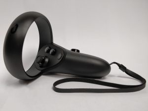 One of the Oculus Quest controllers, showing the ring above the controller and the thin wrist strap.