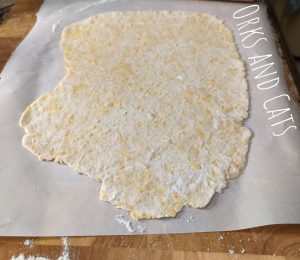 Rolled out cracker dough, floured, on a piece of parchment paper.